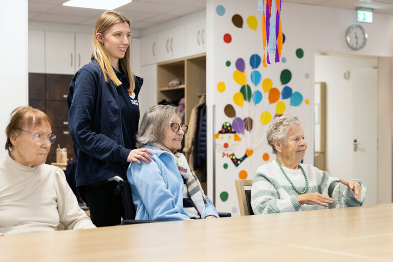 Mitarbeiterin betreut Seniorinnen in der Tagespflege von Herzlich & Gerne in Dortmund-Asseln